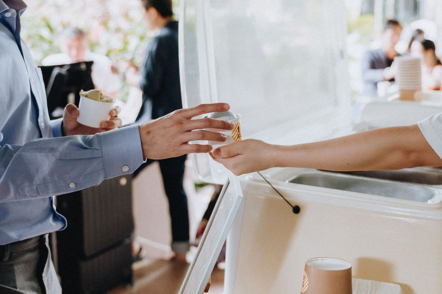 Guest receives a drink cup at an outdoor wedding reception beverage station.