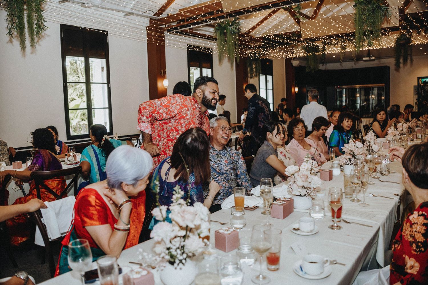 Elegantly decorated wedding reception hall with long dining tables and guests seated together.