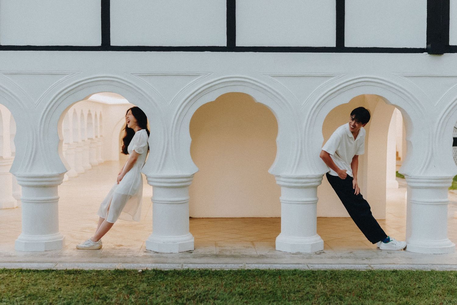Two dancers pose elegantly against white arched columns in a modern artistic composition.
