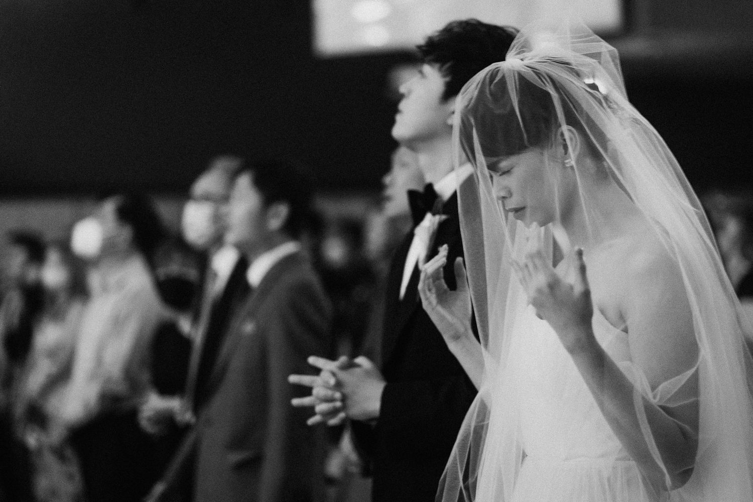 A black and white candid shot of an emotional wedding ceremony moment.