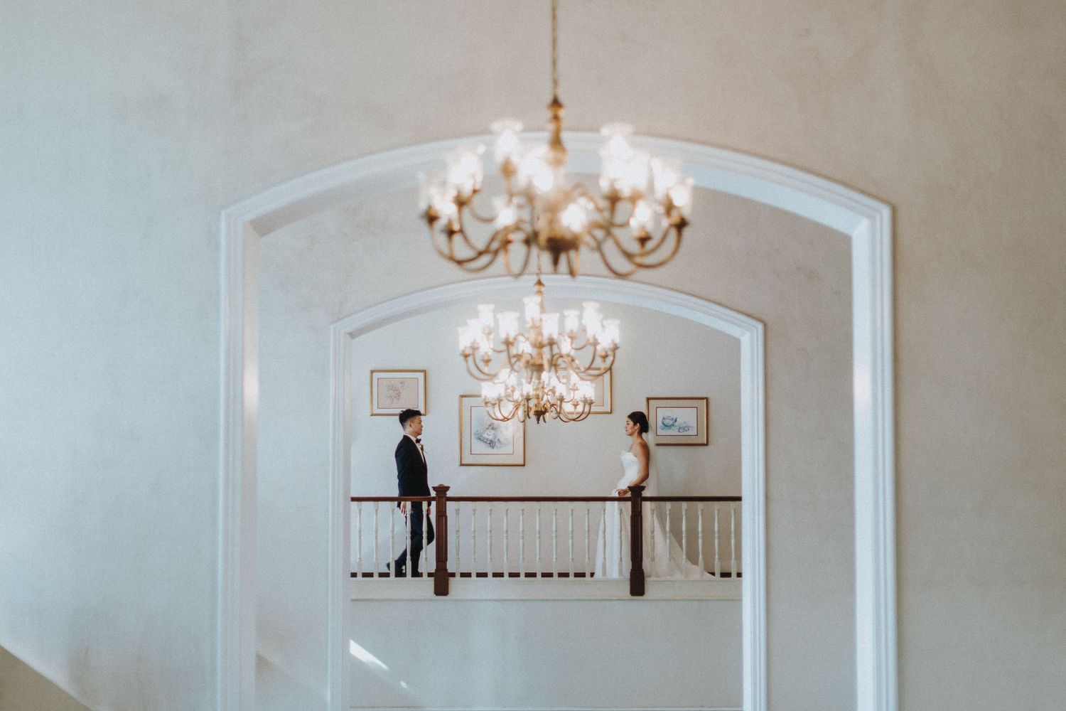 Elegant white interior with chandeliers and arched doorways leading to a reception area.