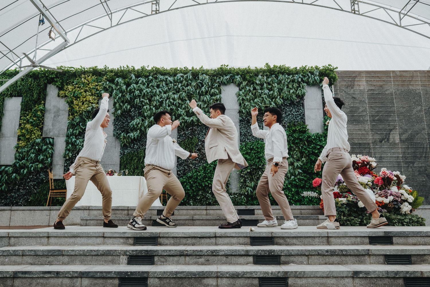 Wedding party performing synchronized dance moves on outdoor stone steps.