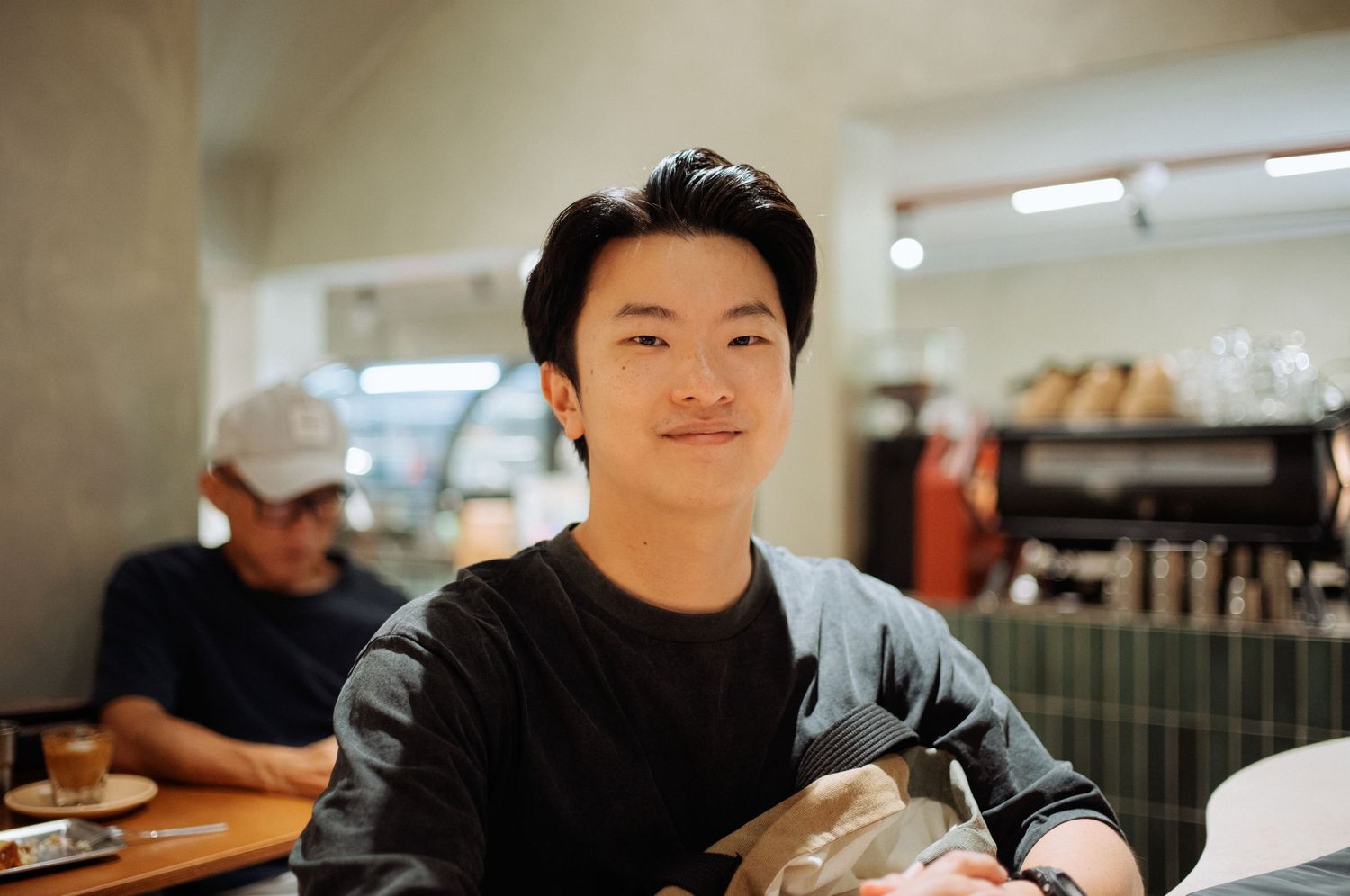 A person in a black sweater sitting at a casual dining establishment.