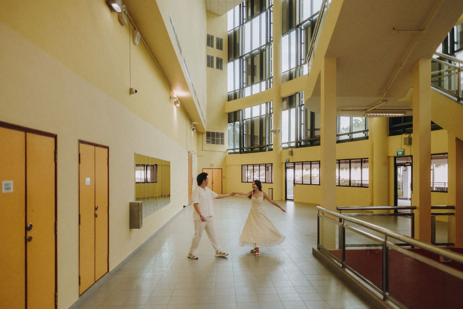 Long corridor view of an institutional building with yellow-tinted lighting and stairs.
