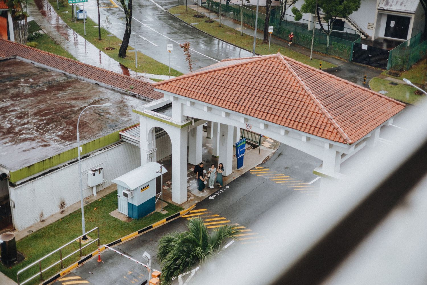 Aerial view of a residential neighborhood with orange tiled roofs and streets after rainfall.