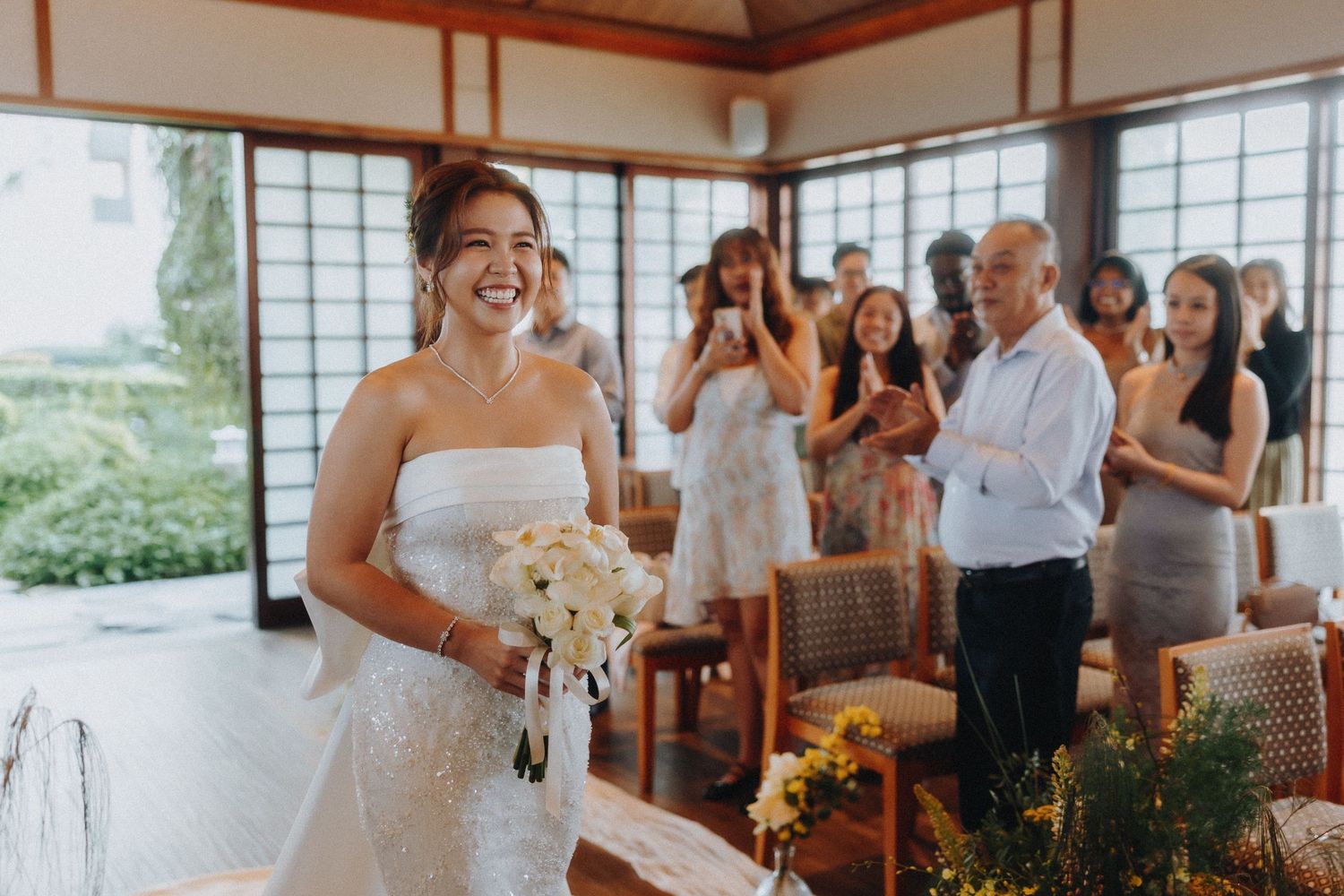 Wedding celebration in a bright Japanese-style room with wooden beams and large windows.