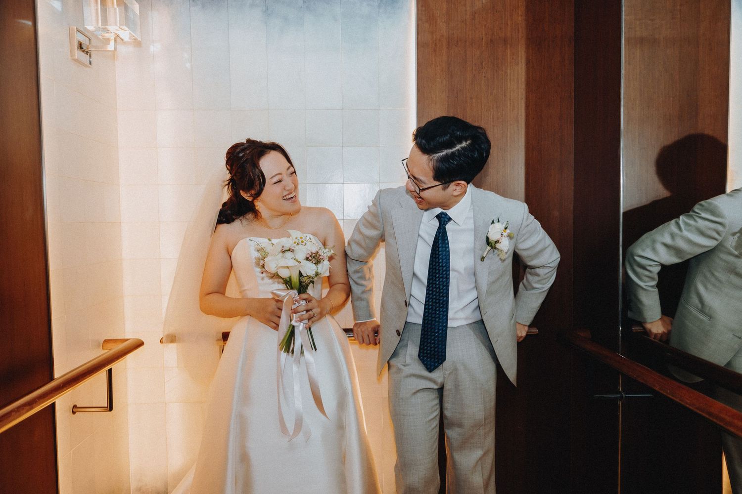 Couple walking through a modern hotel corridor during their wedding day.