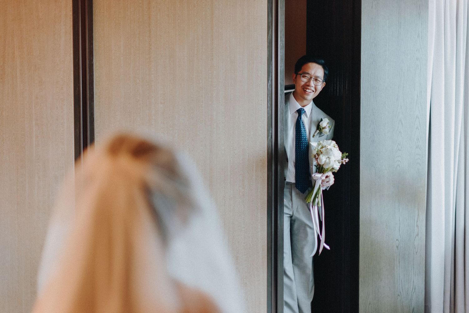 A romantic wedding moment captured in front of a white backdrop with floral arrangements.