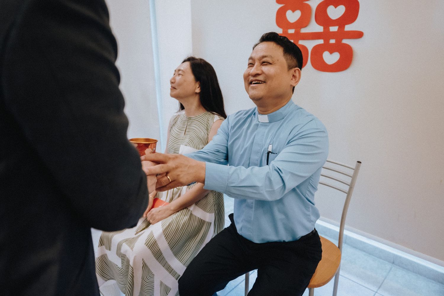 Man smiles while receiving tea during traditional Chinese wedding tea ceremony.