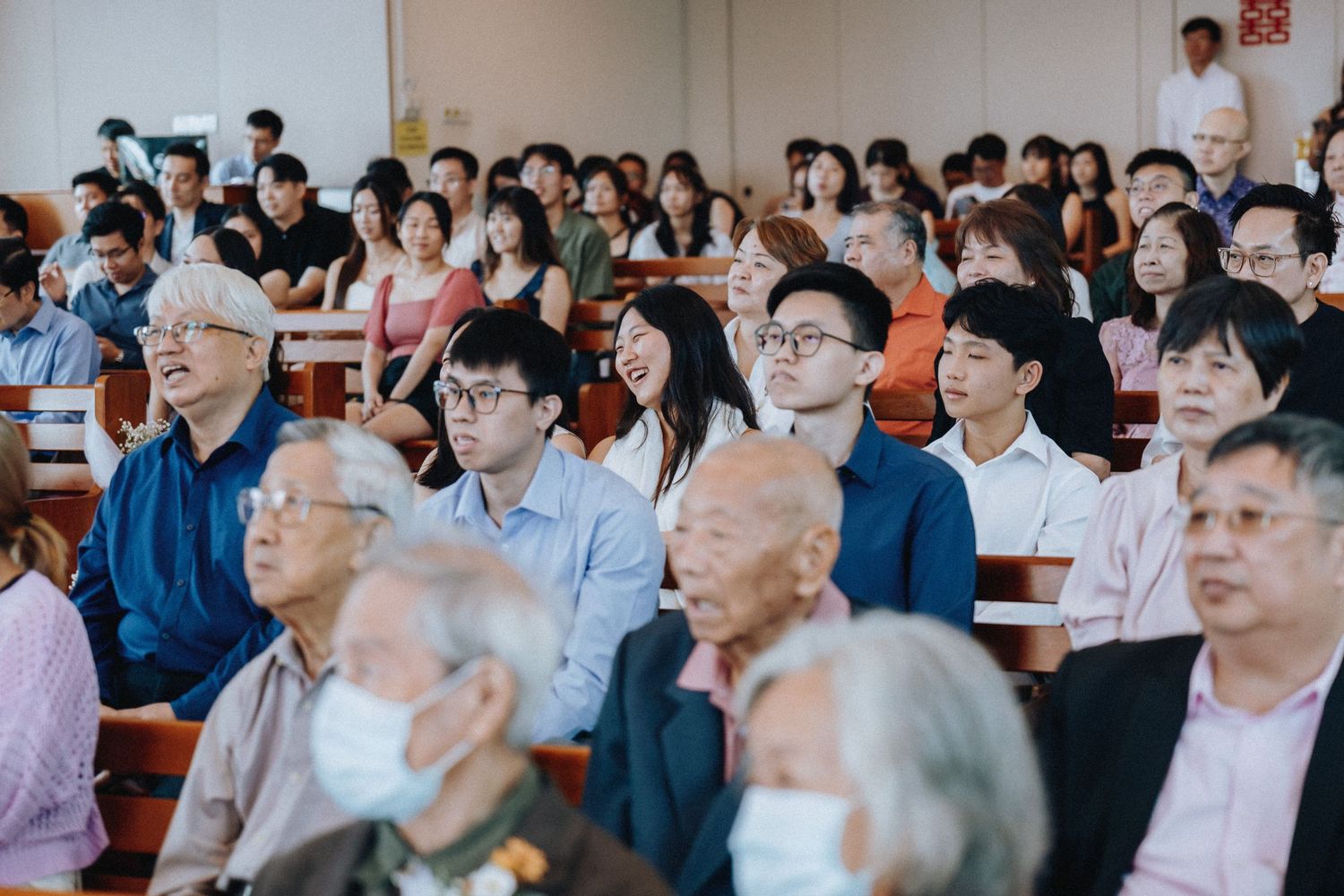 Diverse multigenerational wedding guests seated in church pews attending a wedding ceremony.