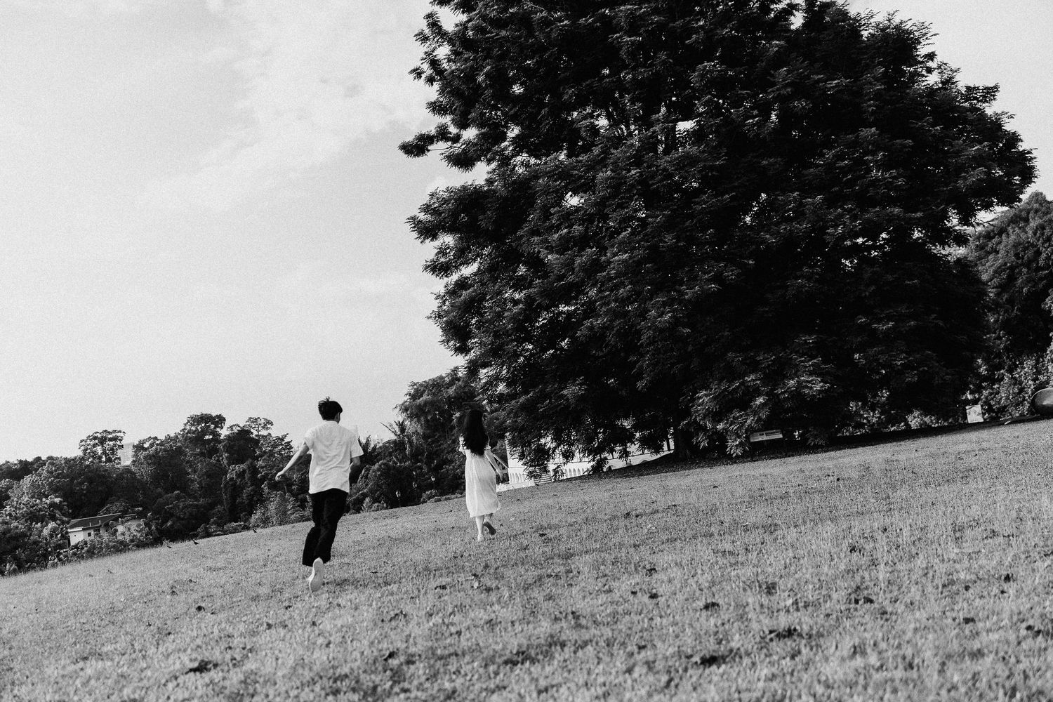 Two figures walk uphill across a grassy slope in a black and white landscape photograph.