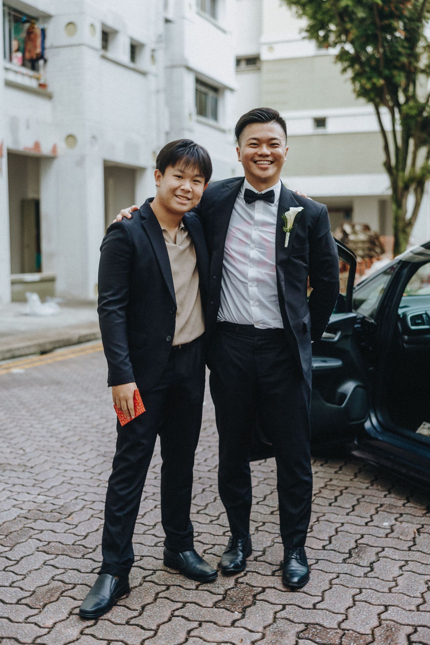 Wedding party members in formal attire posing together on a cobblestone path.