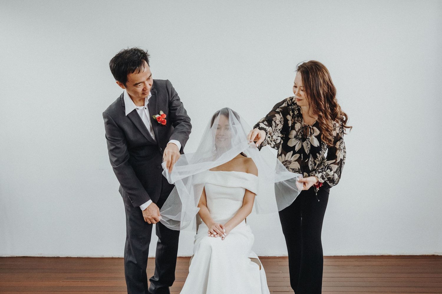 Wedding preparation scene with multiple people helping with final touches in a bright indoor setting.
