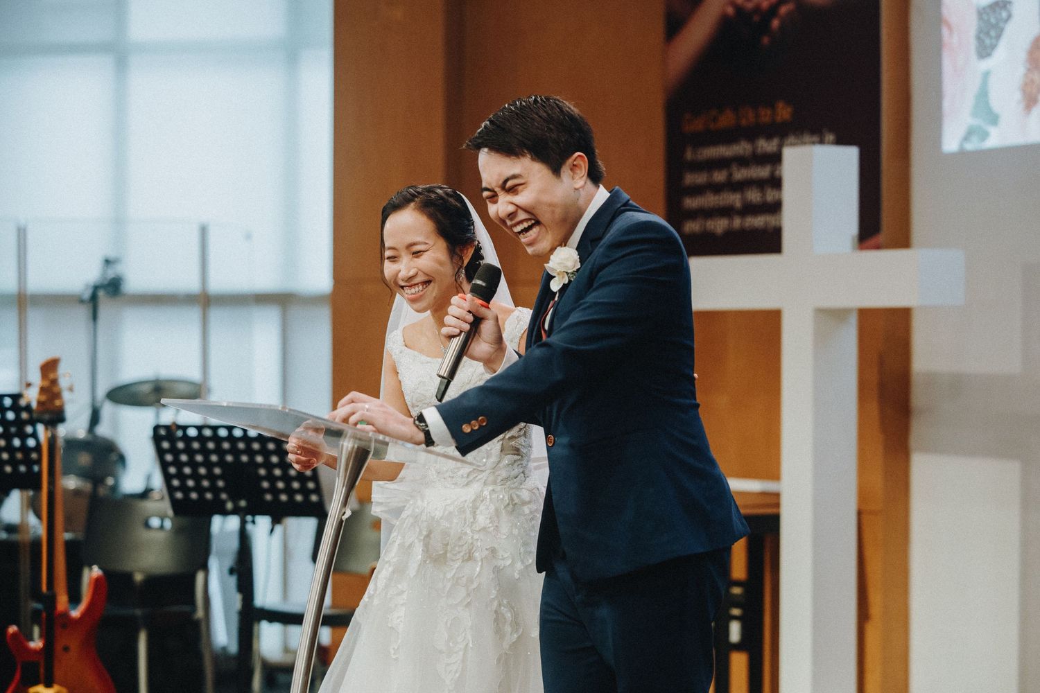 Indoor wedding ceremony with couple sharing emotional moment in modern venue with white decor.