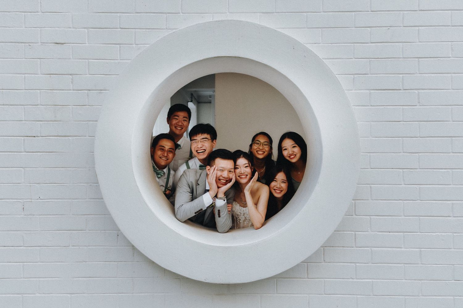 Artistic wedding photos captured through oval-shaped frames on a white brick wall.