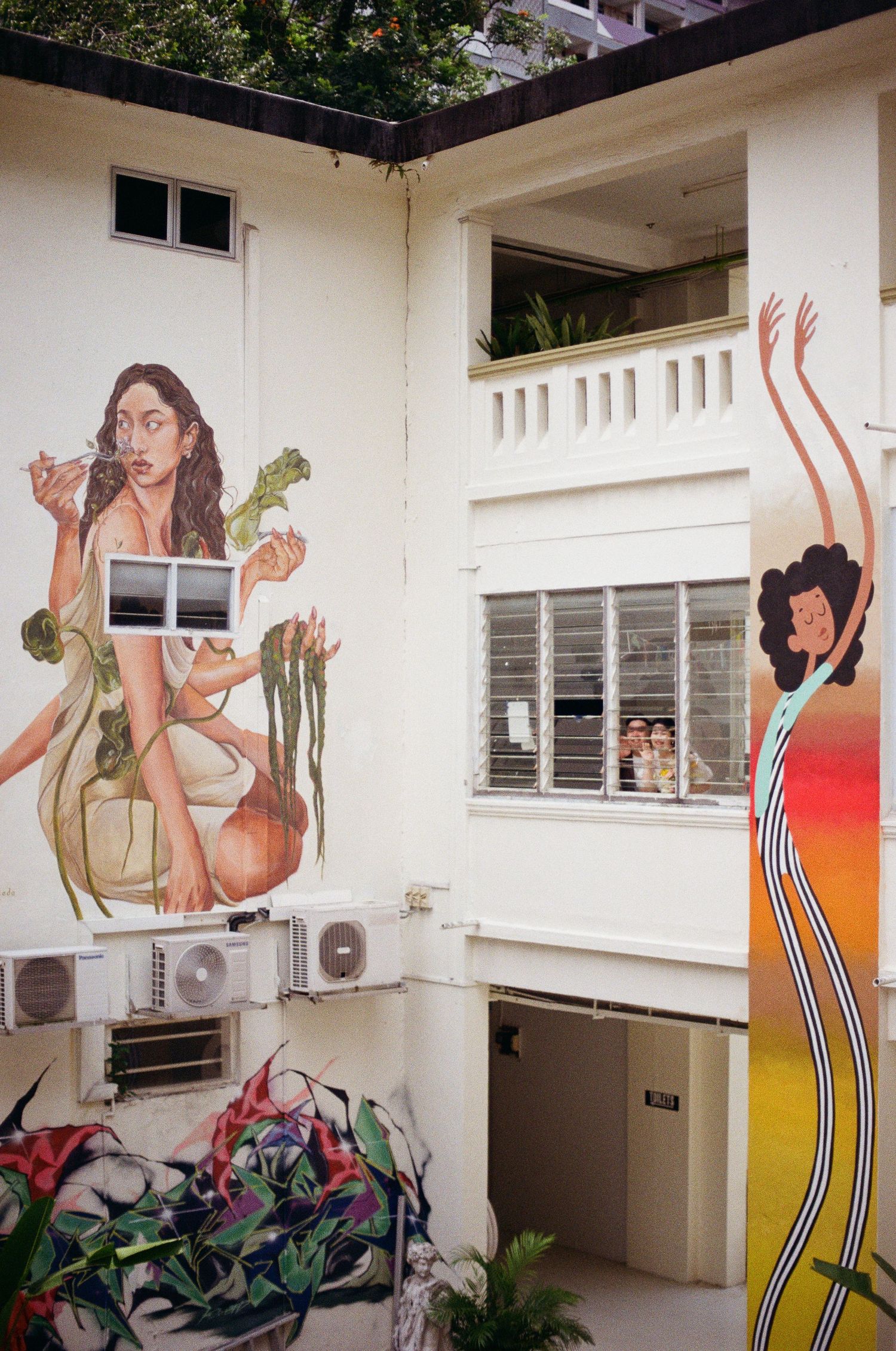 Colorful street art murals painted on a white building wall featuring retro-style figures and designs.