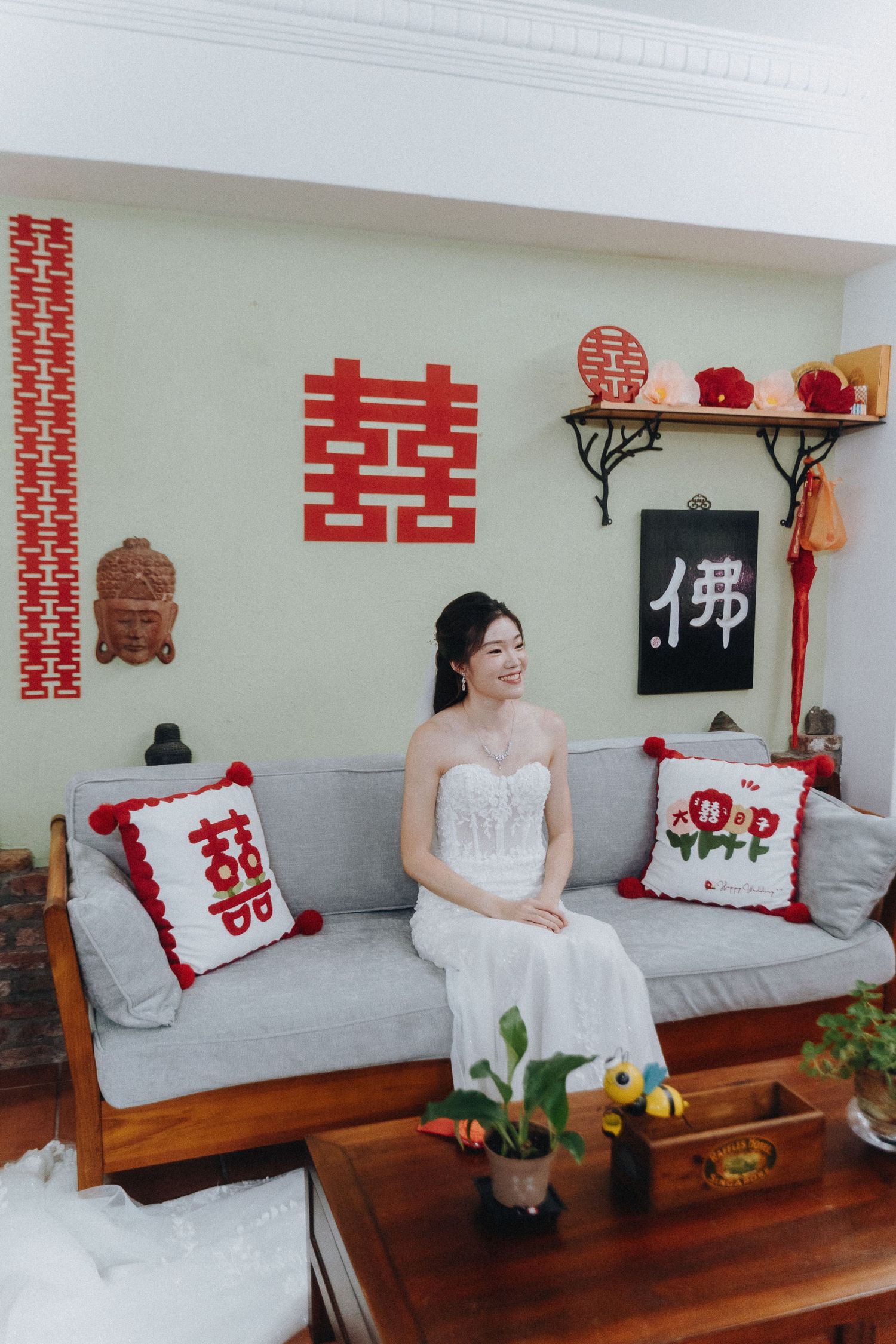 Traditional Chinese wedding decor with red double happiness symbols and white cushions on wooden benches.