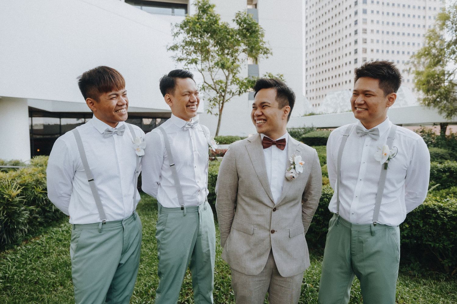 Wedding party in mint green pants and white shirts standing together outdoors.