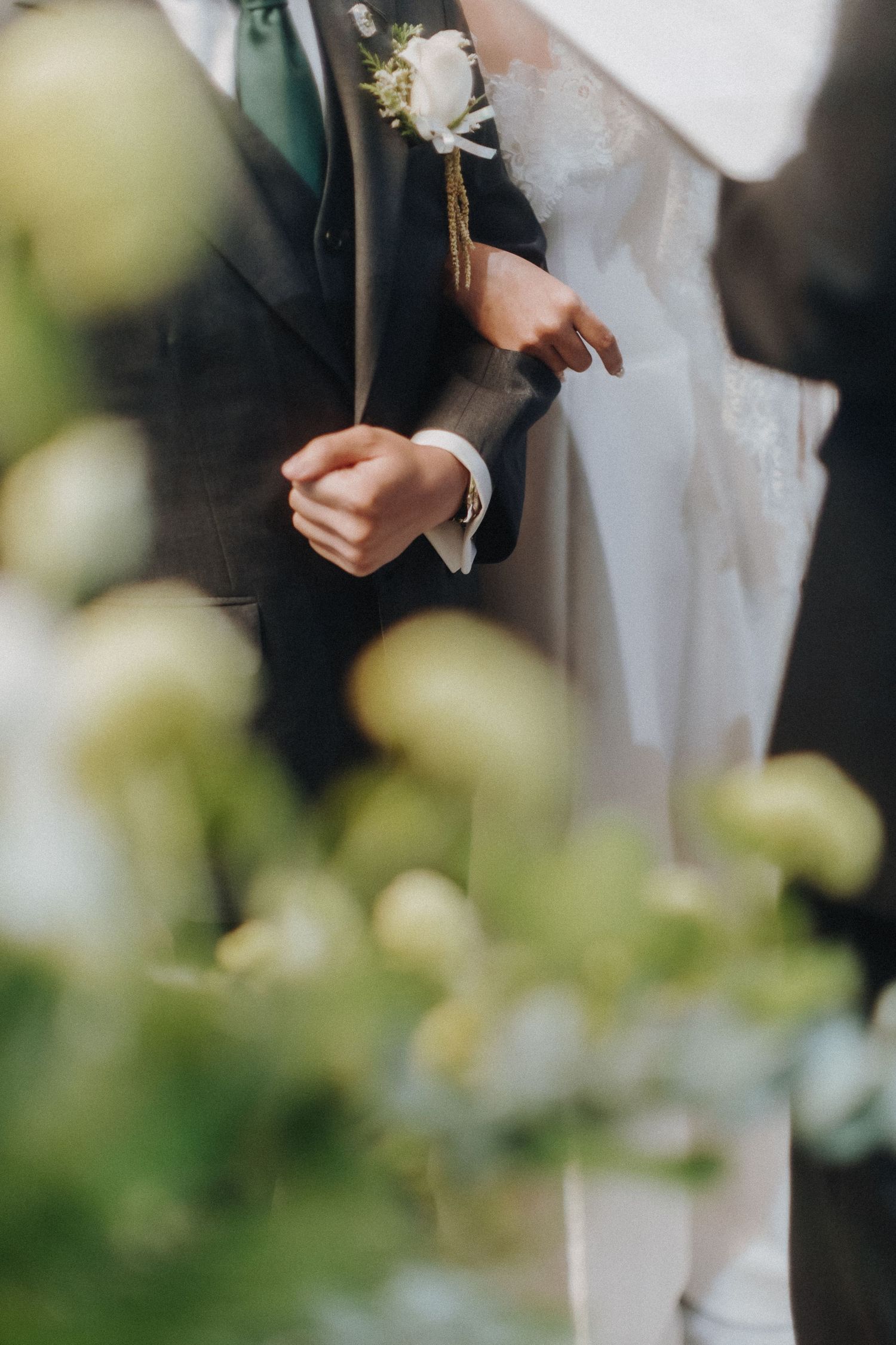 Close-up of formal attire with a white boutonniere against a blurred green background.