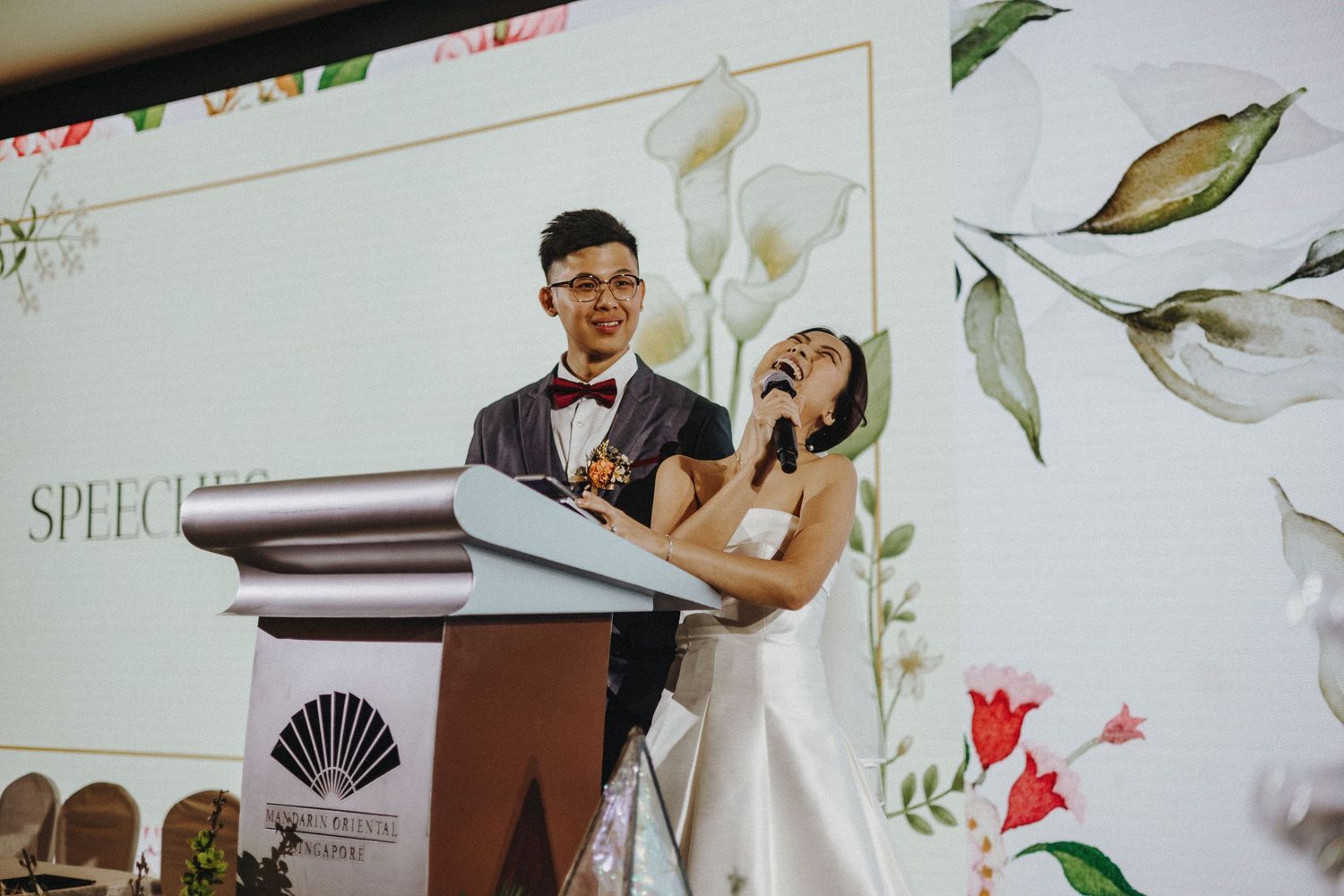 Wedding venue decorated with floral wallpaper features a wooden podium and chairs arranged for a ceremony.