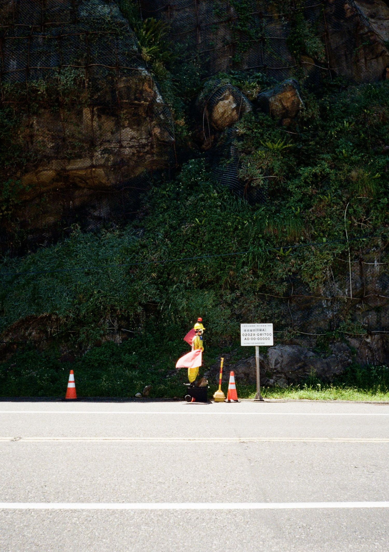Empty parking area against a stone wall with safety cones and warning signs visible.