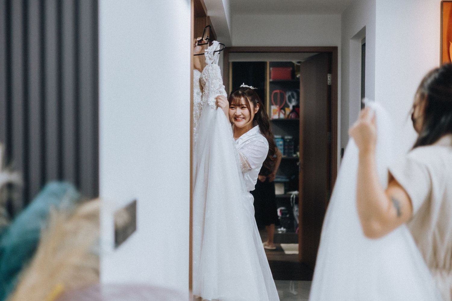 A bride in a white wedding dress stands in front of a mirror while getting ready for her special day.