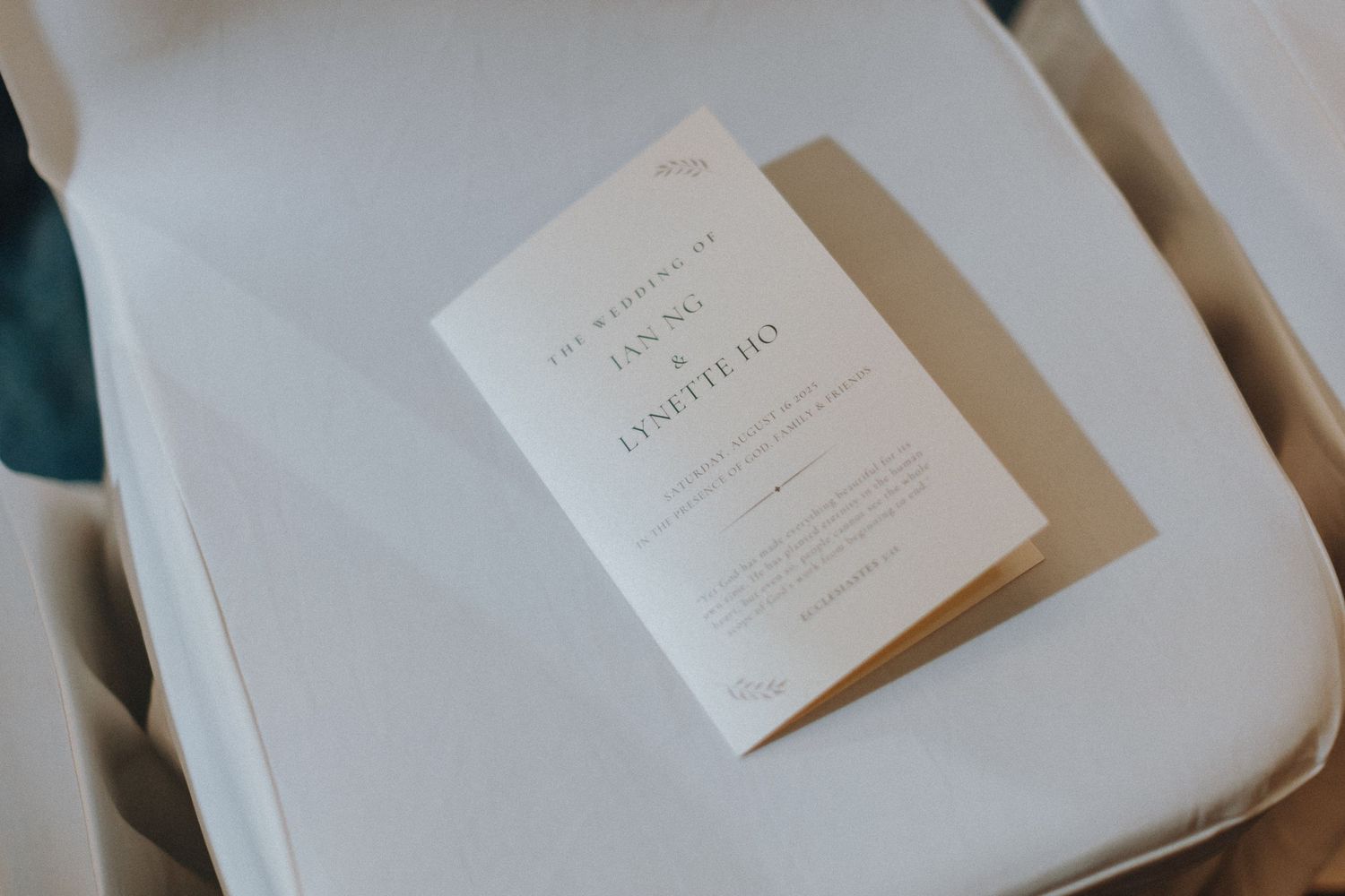 Minimalist wedding invitation displayed on white surface with soft shadows.