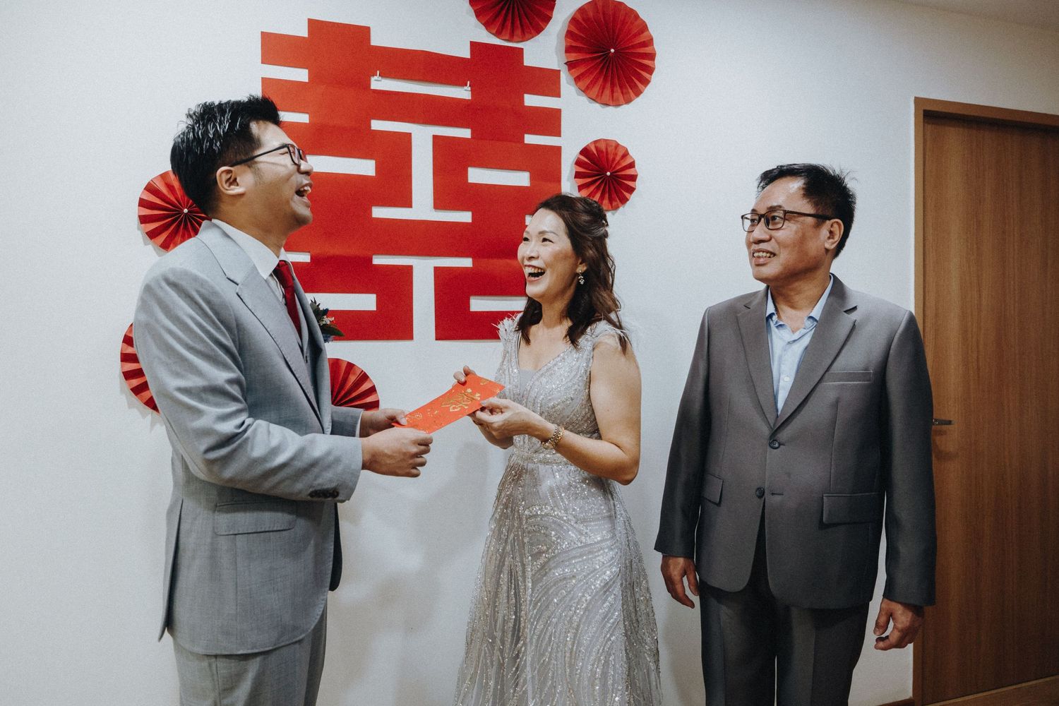 Wedding ceremony with traditional Chinese double happiness symbol and red paper fans as wall decorations.