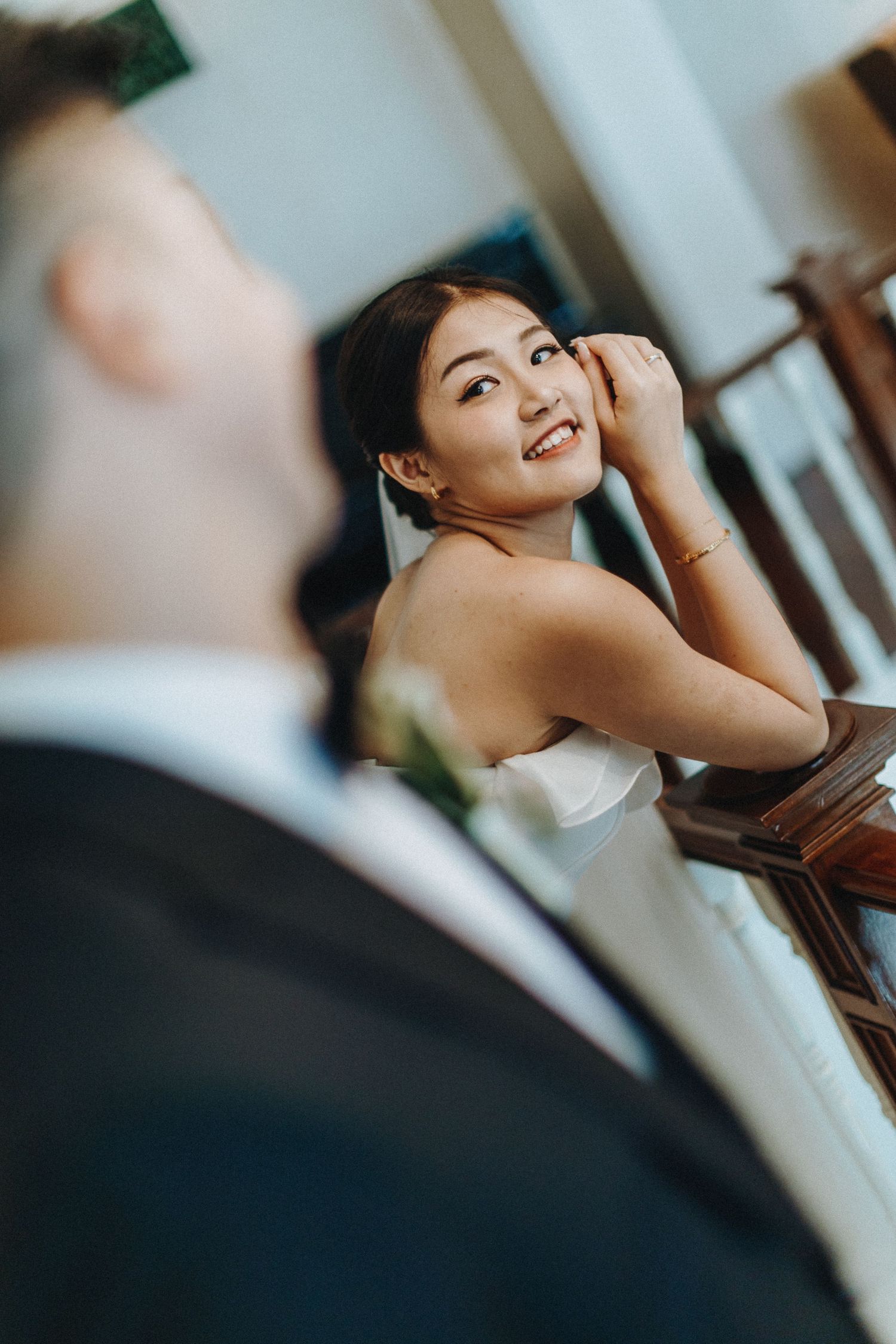Bride in a white wedding dress smiles joyfully during a wedding celebration.