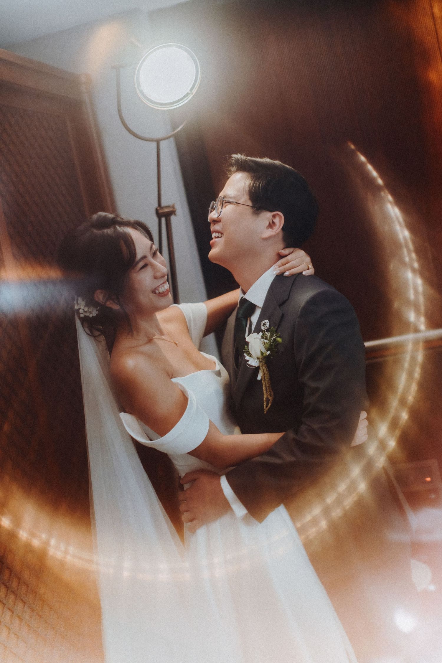 A romantic wedding portrait captured with warm lighting and artistic lens flare effects.
