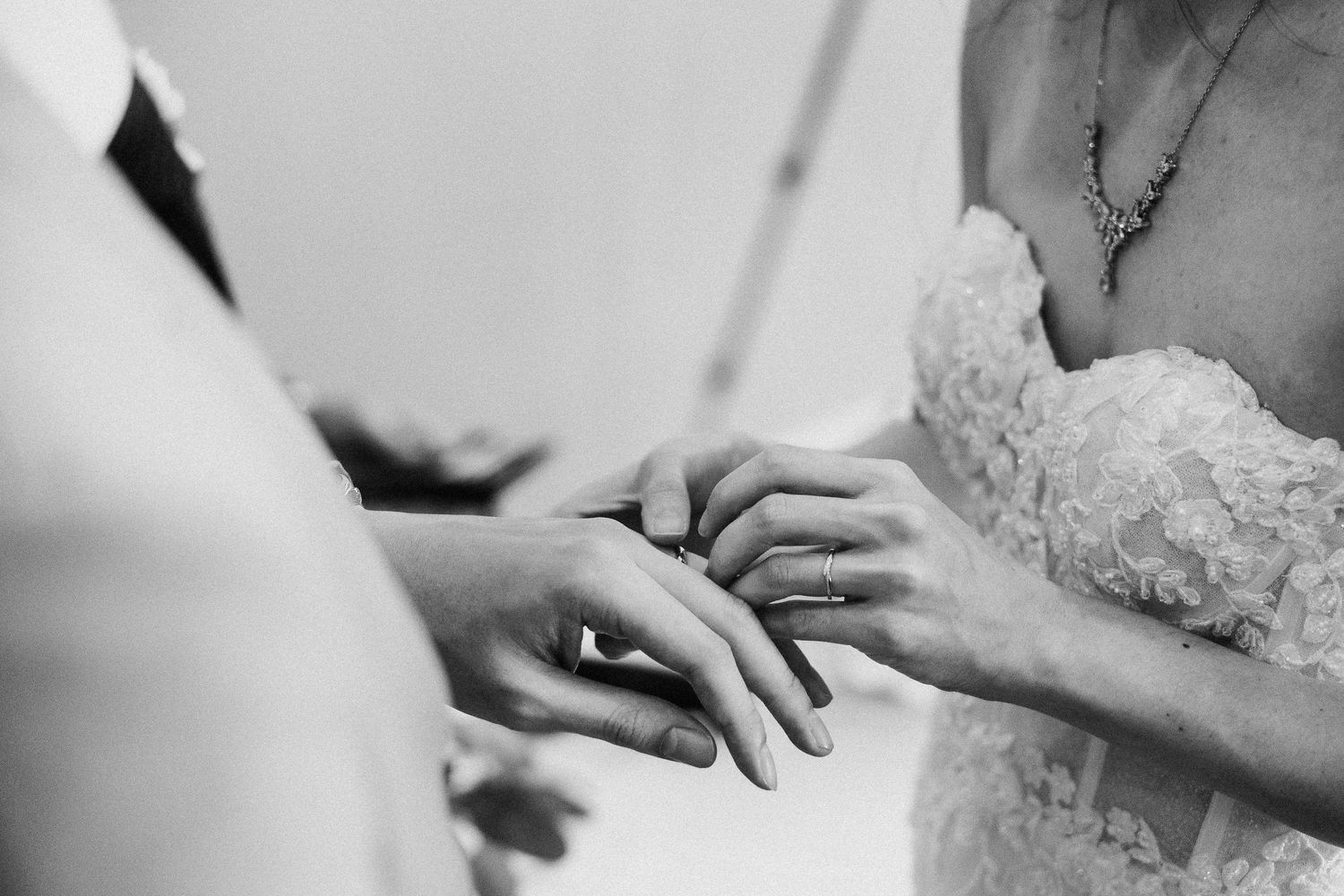 Close-up shot of hands during a ring exchange ceremony at a wedding.