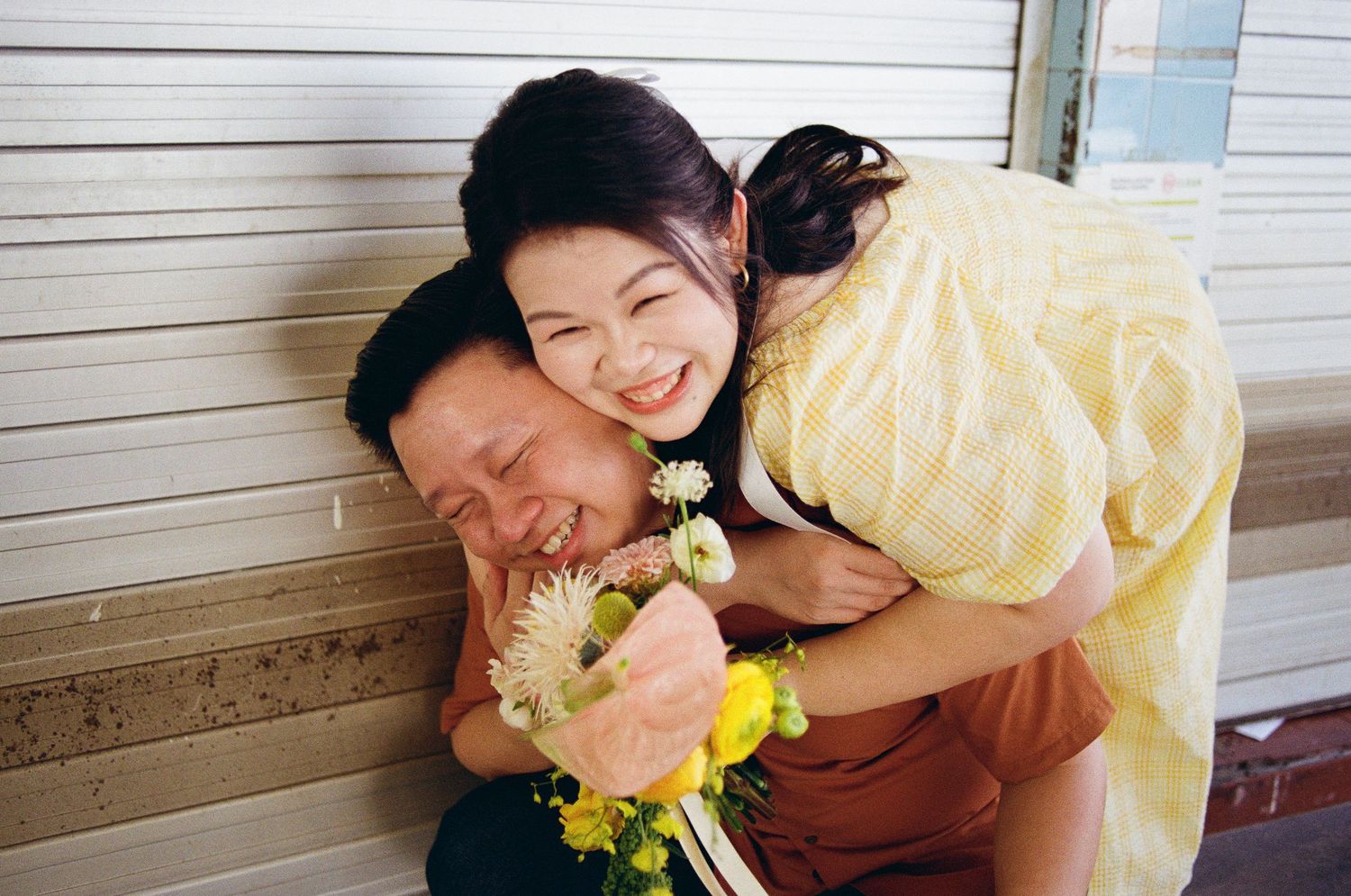 A playful moment captured during a wedding photoshoot with yellow flowers and a yellow dress.