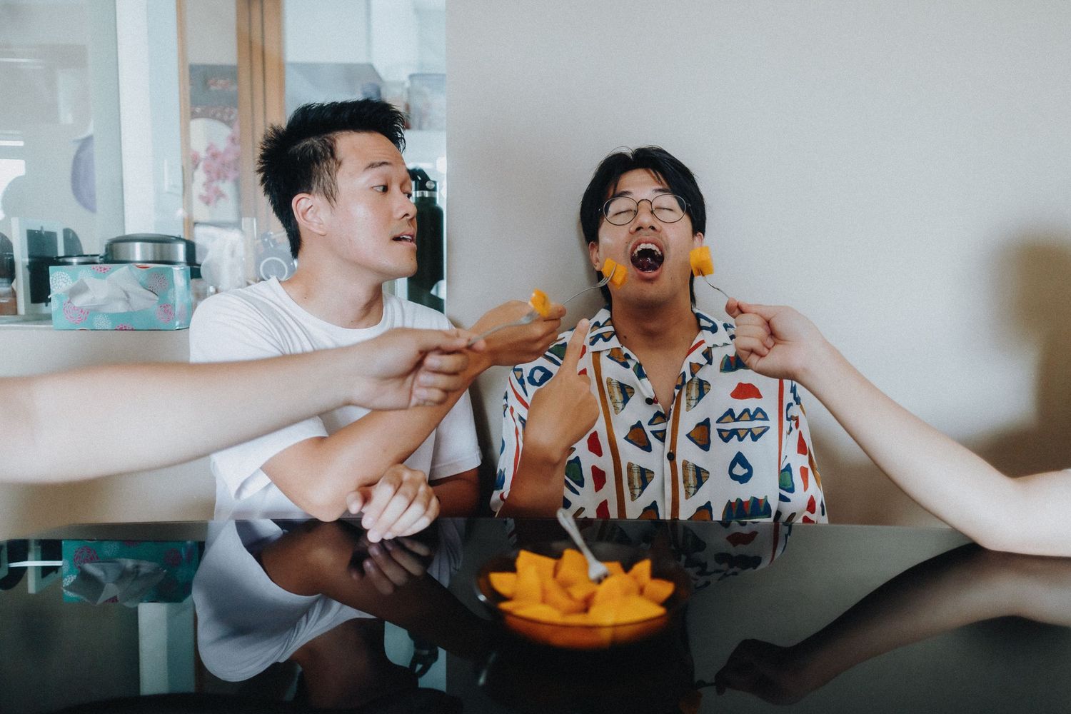 Group of friends sharing french fries and laughing together while gathered around a table.