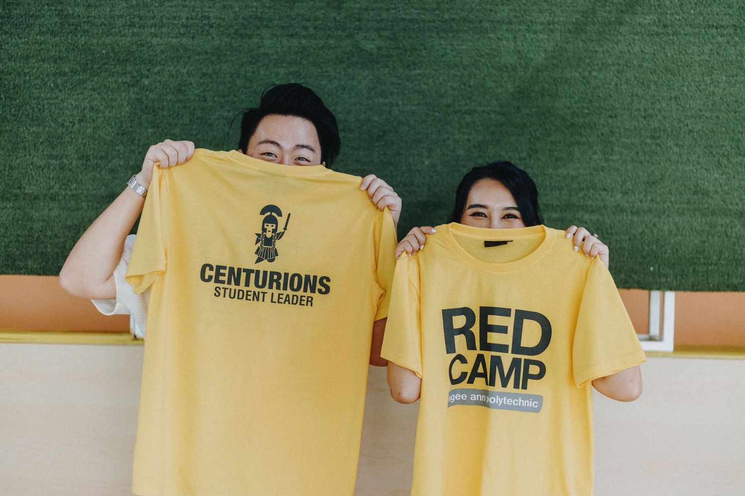 Yellow t-shirts displayed against a green background in a studio setting.