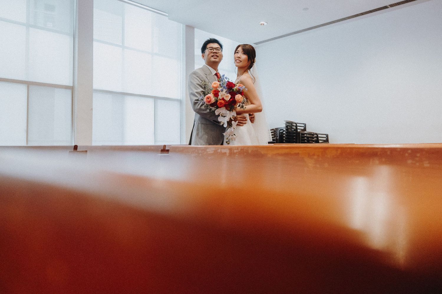 Wedding couple photographed from a creative low angle through wooden furniture.