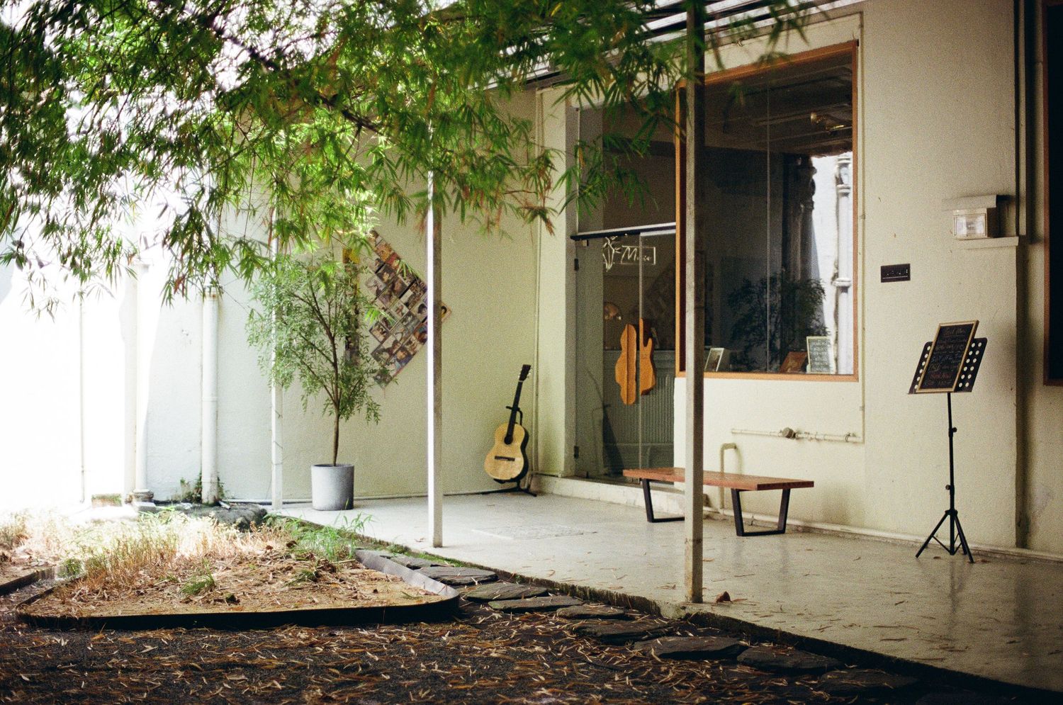 A peaceful entrance area with a guitar, music stand and potted plants on a concrete porch.