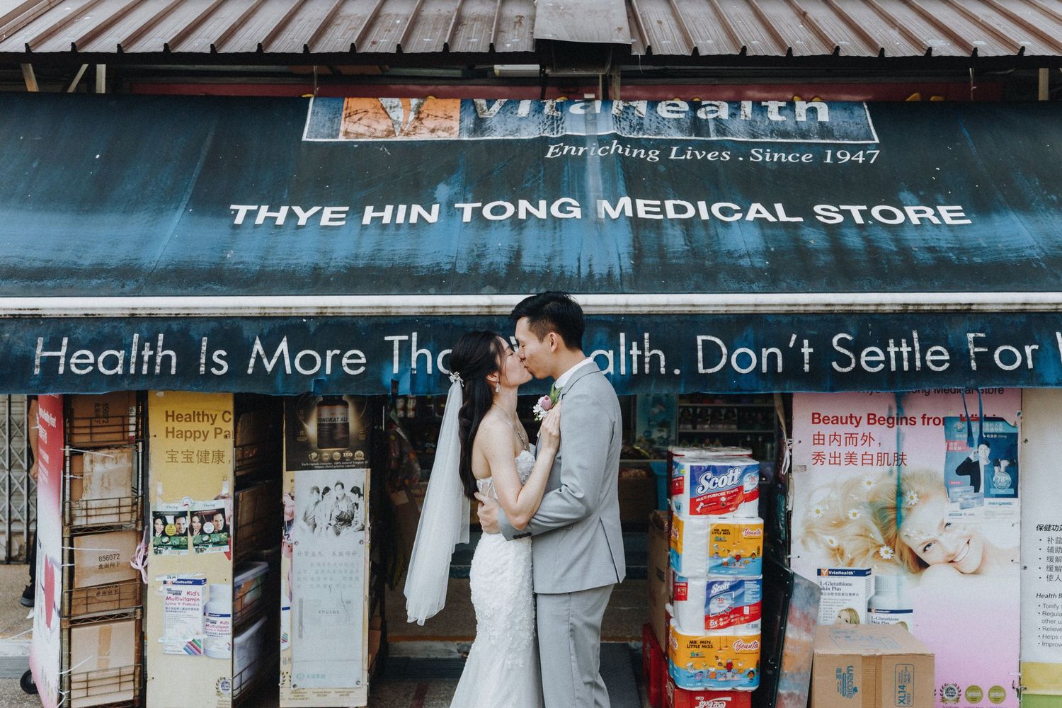 Exterior view of various shop signs and storefronts along an Asian medical store strip.