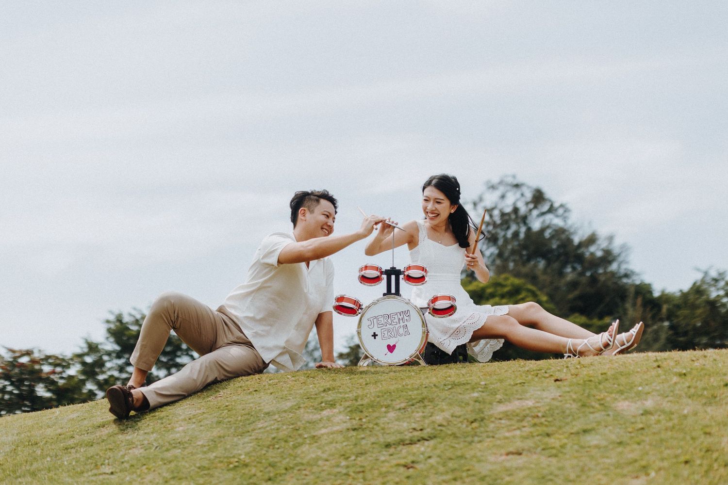 Panoramic view of a couple having a romantic picnic on a hilltop meadow.