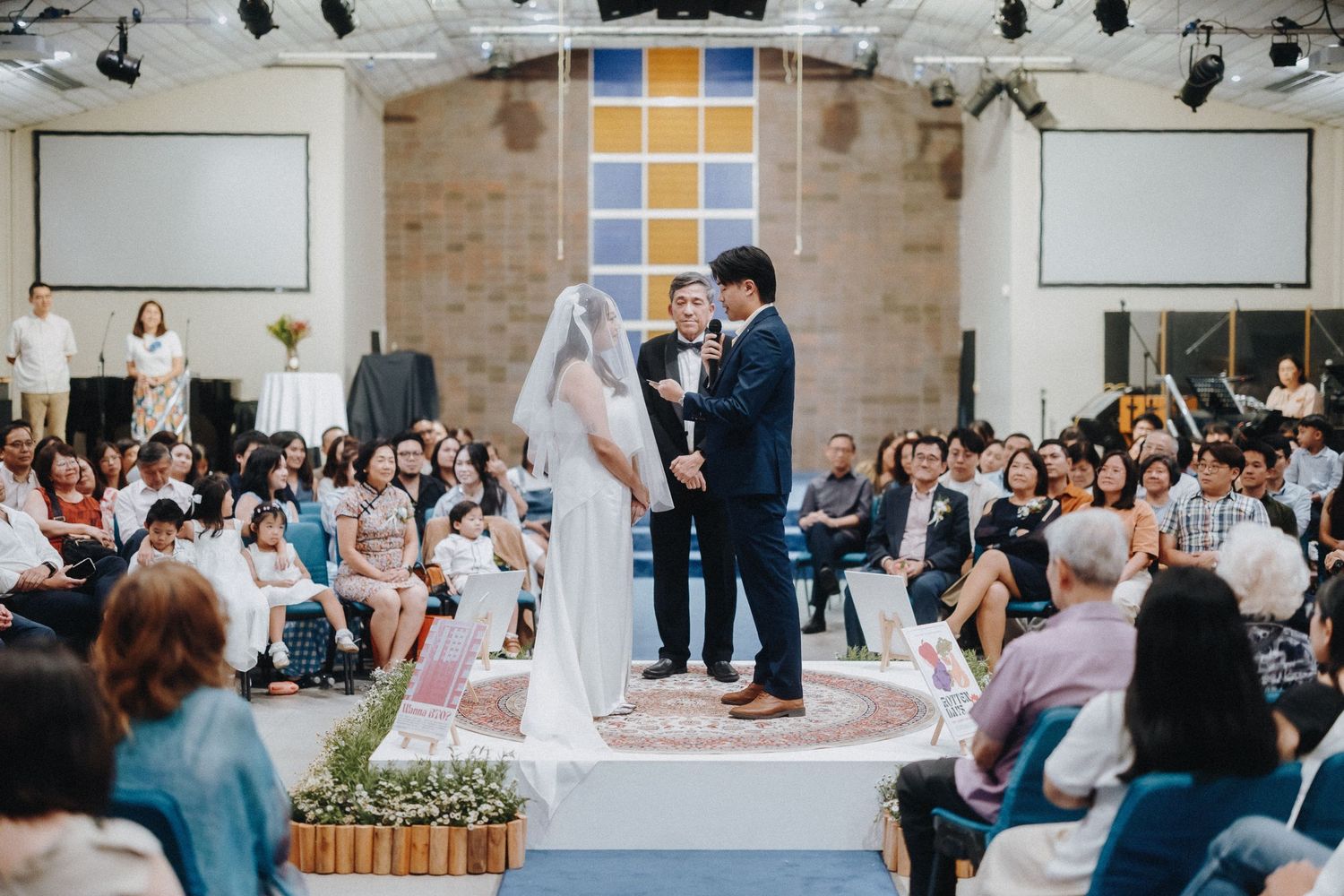 A wedding ceremony in progress at a modern church venue with audience in attendance.
