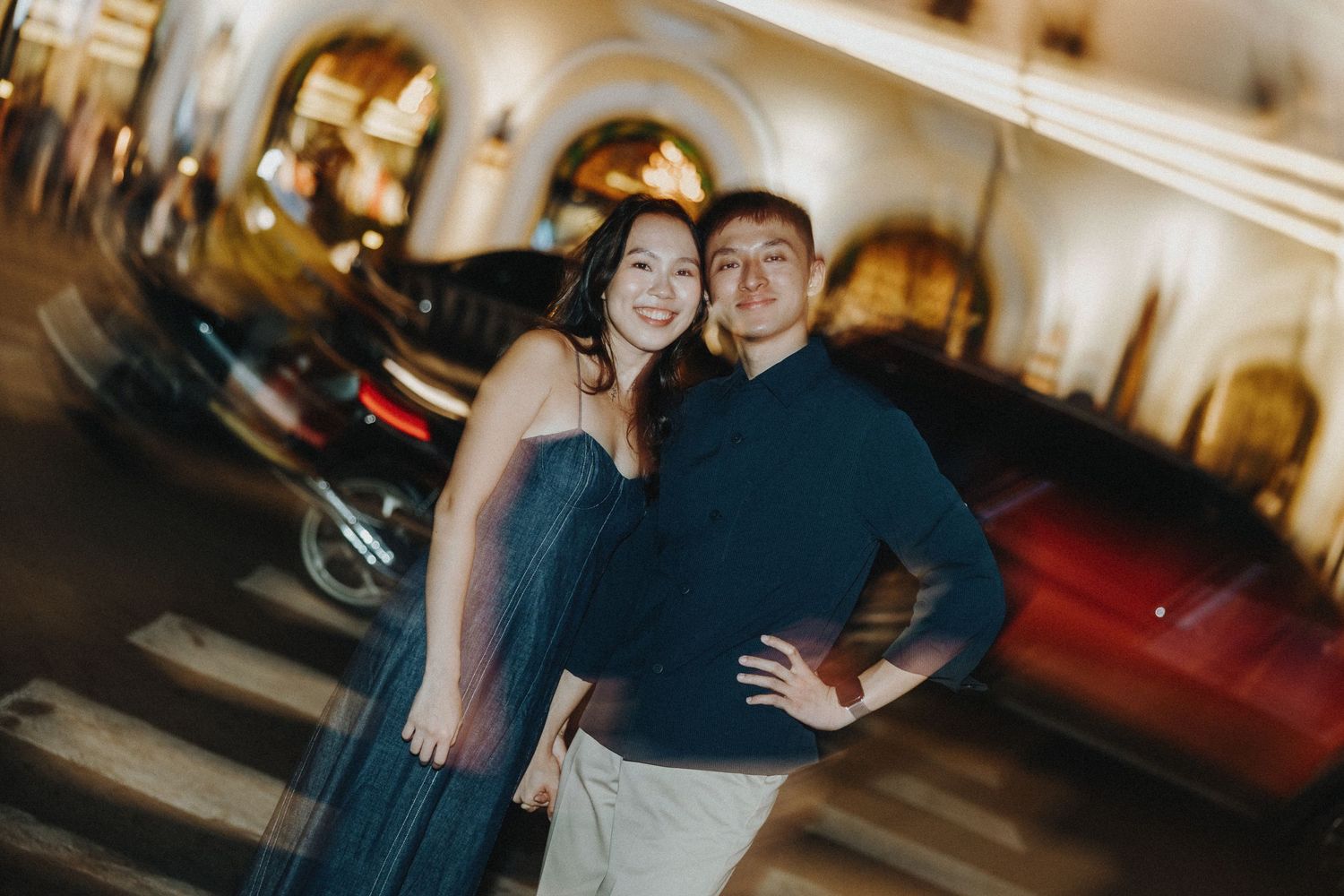A romantic engagement photo session captured in a warmly lit urban setting.