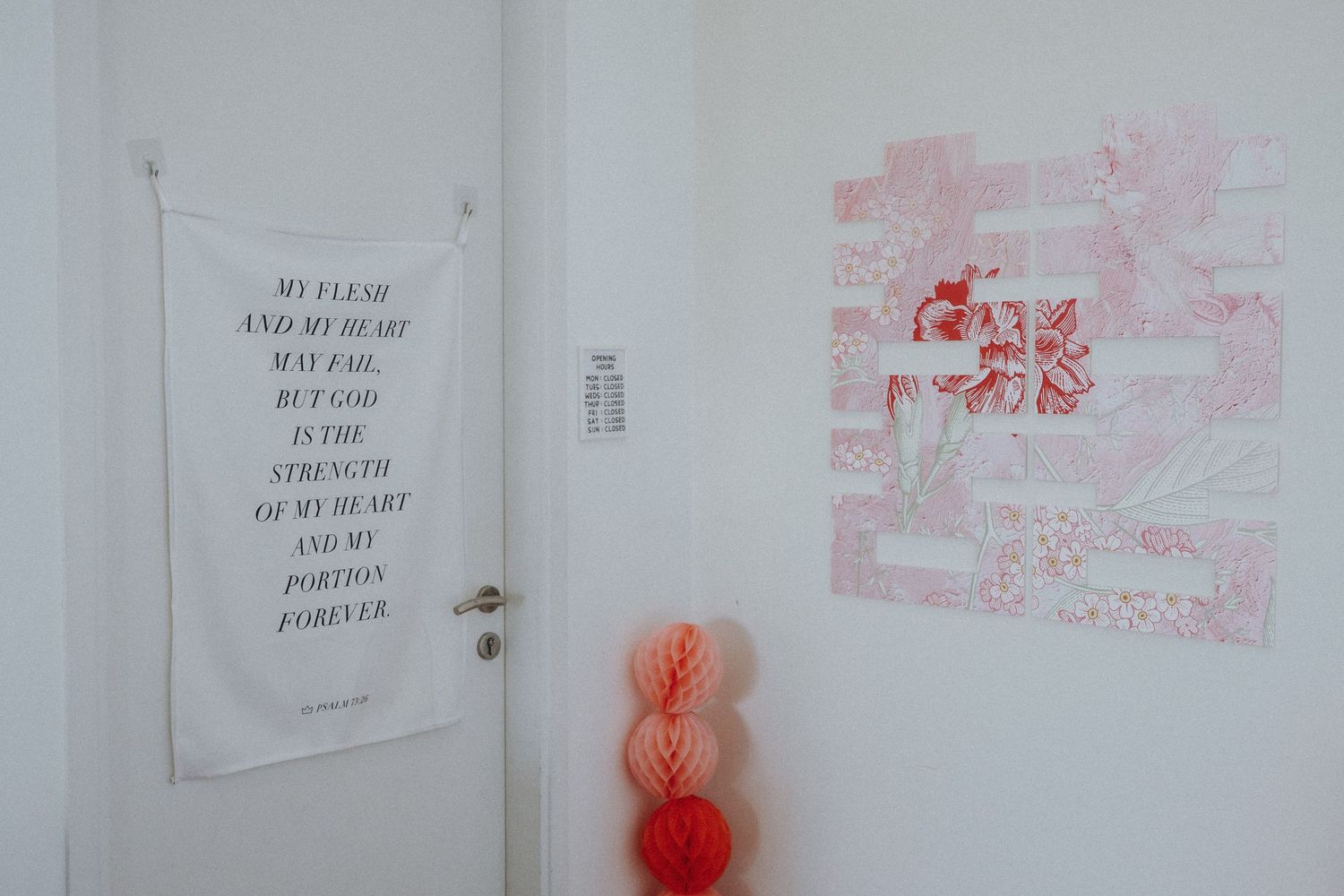 A white door with text poster and pink wall art decorations.