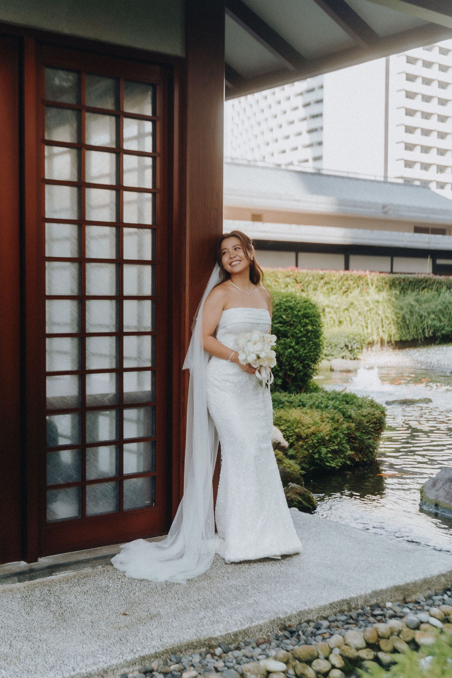 Elegant bridal portrait near Japanese garden pavilion with water feature.