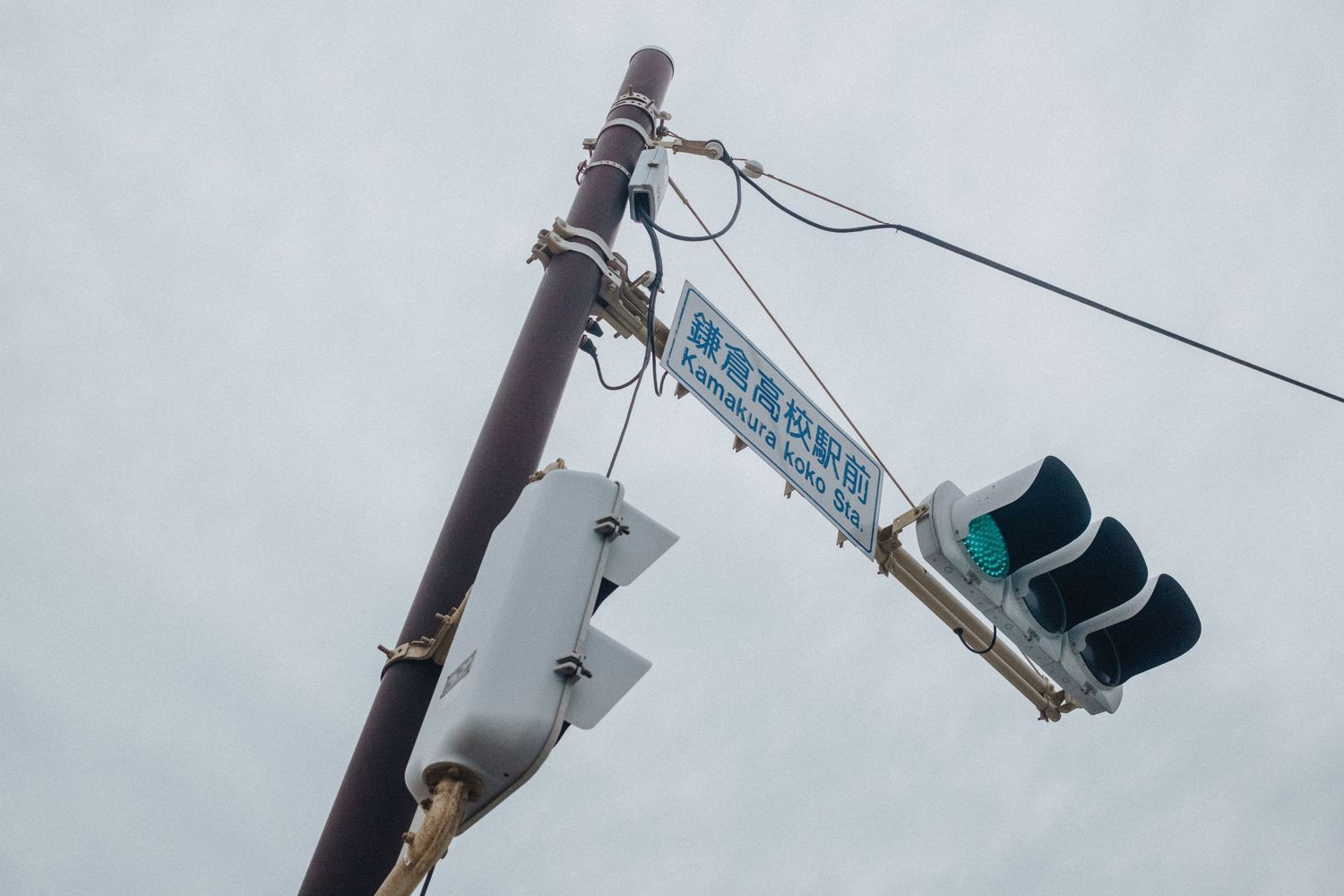 Traffic signals and poles against a cloudy sky.