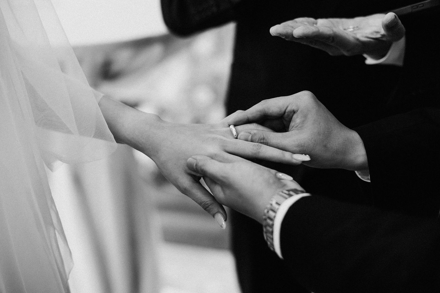 Monochrome detail shot of hands holding during a wedding ceremony.