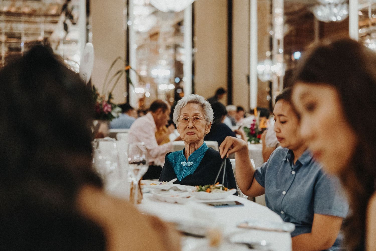 Wedding reception guests enjoying meal at decorated dining tables.