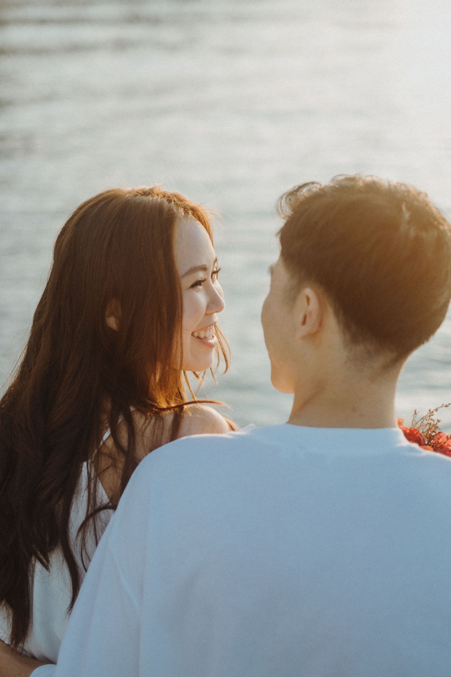 A loving couple gazes at each other with the sparkling ocean in the background.