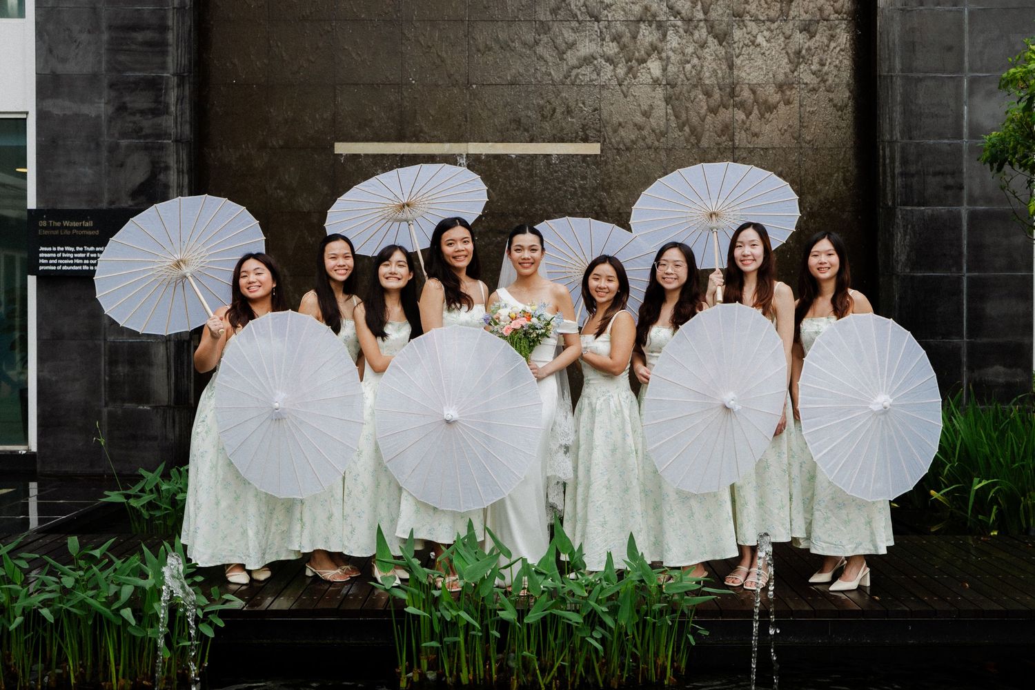 Bride and bridesmaids in mint dresses holding white parasols at wedding.