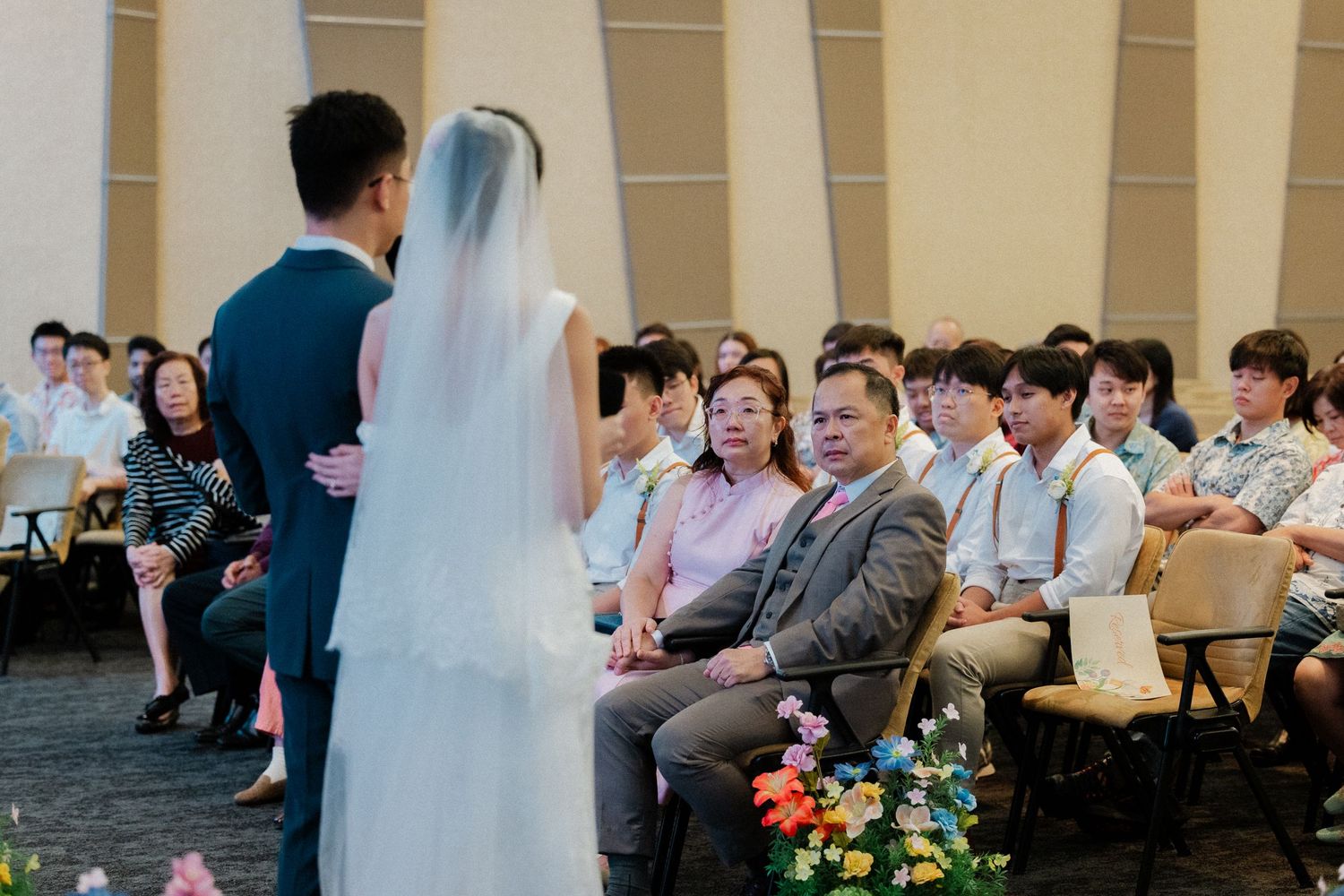Asian bride and groom stand at the altar as guests watch their elegant wedding ceremony.