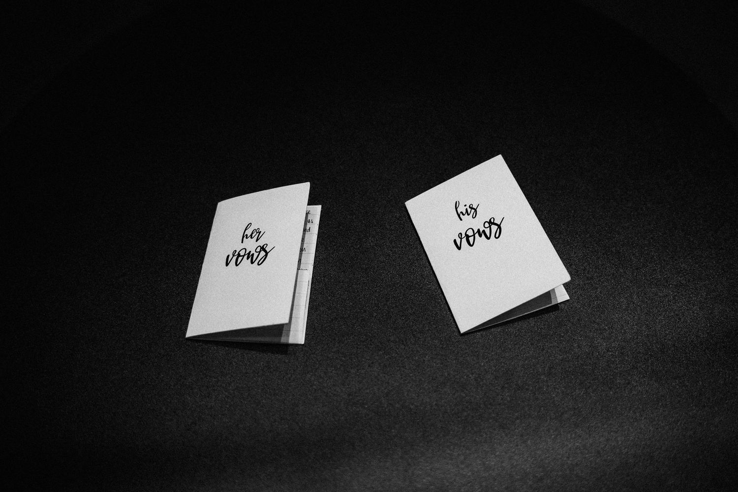 Two white wedding vow books photographed on dark background.