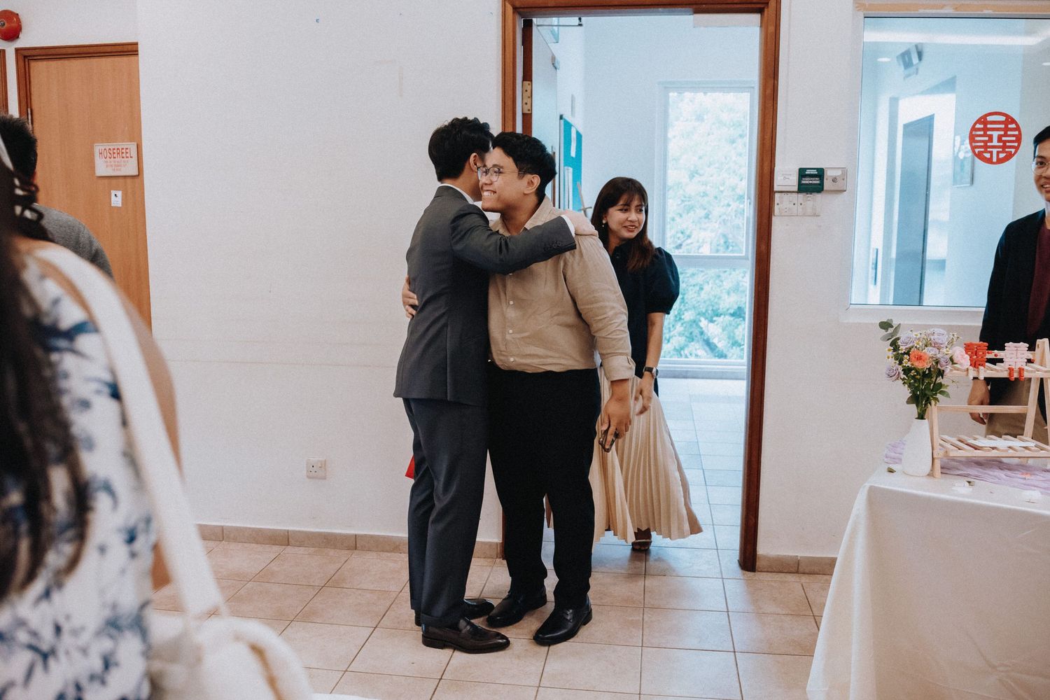 Groom sharing warm embrace with guest at wedding reception entrance.